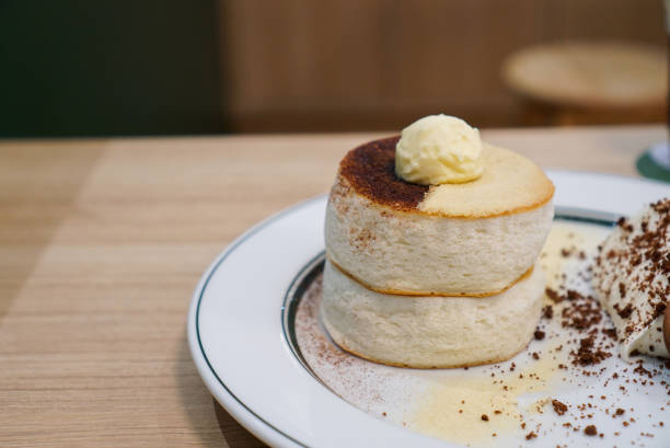 A plate of fluffy pancake with smooth and softly texture, topped with butter, cocoa powder and malt. (isolated)