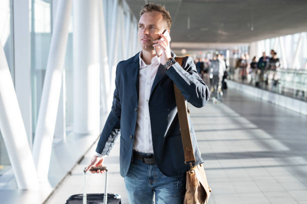 istock Young man walking through airport gate and talking on phone 1301140157