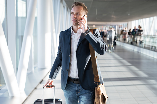 Young man walking to airport gate and talking on phone