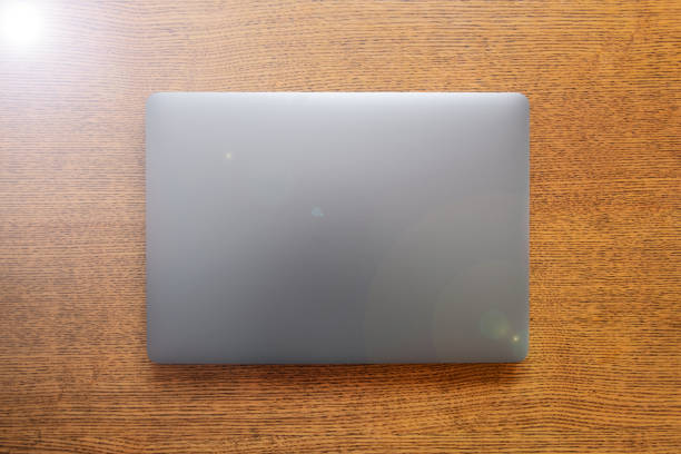 istock Gray metallic laptop closed on wooden background.. Communication network. Silver metal surface. 1301141222