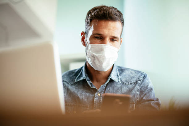 istock Young businessman with a mask working in his office on laptop 1301145668