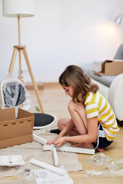 Little girl assembling furniture in a new home - moving into a new home concept. Little girl assembling furniture in a new home - moving into a new home concept. hobbyist stock pictures, royalty-free photos & images