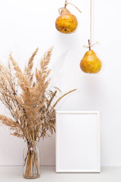 istock Modern still life with white blank photo frame. Summer composition with pampas grass and pears on a light background. Mockup 1301148688