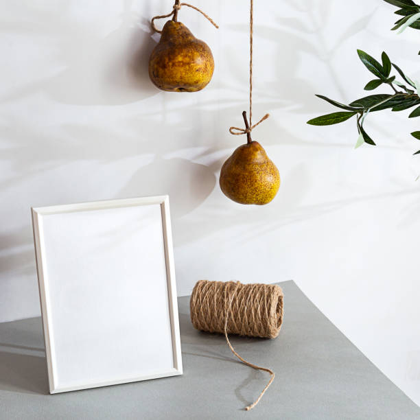 istock Modern still life with white blank photo frame. Summer composition with pears and olive branch shadows. Mockup, on a light background 1301148689