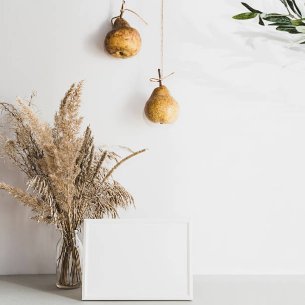 Modern still life with white blank photo frame. Summer composition with pampas grass and pears on a light background. Mockup