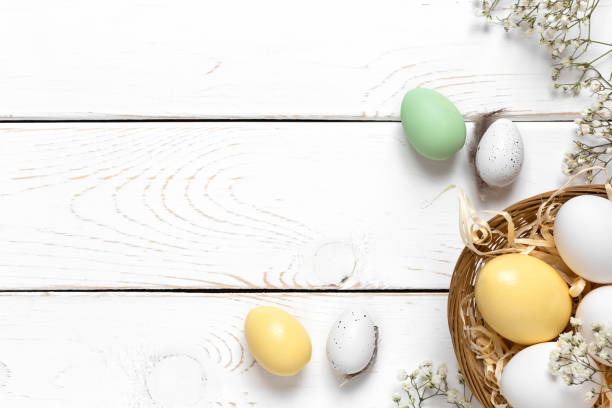 istock Easter background with colorful eggs in a basket on a white wooden background. Top view with copy space 1301150184