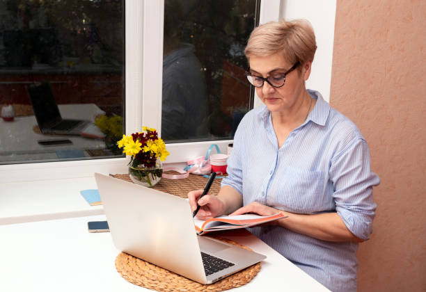 istock A woman makes notes in a notebook with a pen, sitting at a laptop. Selective focus. 1301154132