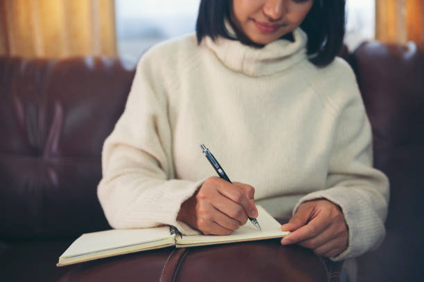 istock Asian student read and write diary book. Planner write meeting agenda on 2021 Calendar, work at home office. Hand of Woman planning daily appointment and note.Calendar reminder event concept. 1301155203