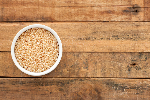 Top view of white bowl full of thai rice over wooden table