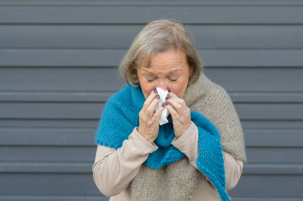 istock Senior woman blowing her nose on a tissue 1301159413