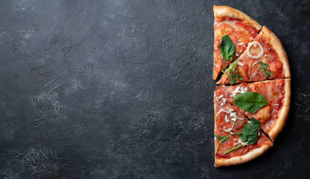 istock Half pizza with greens on dark stone background, space for text 1301160246