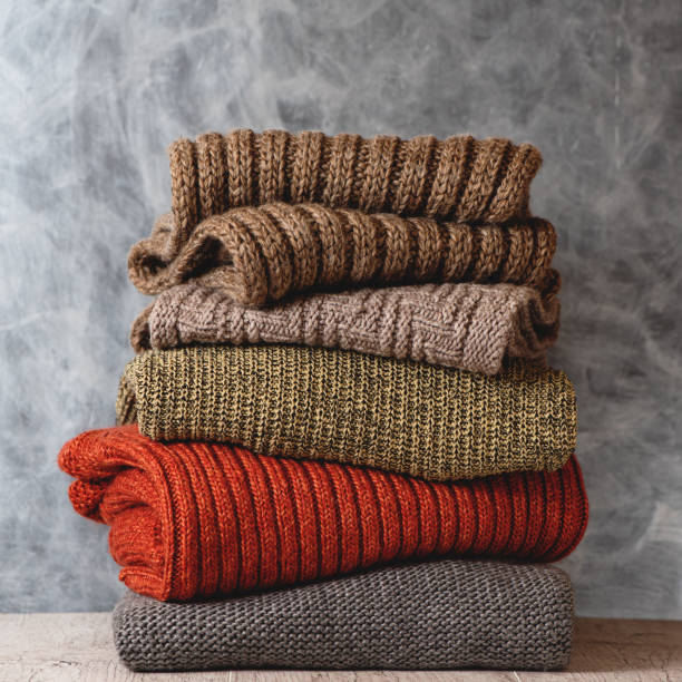 stapel von gefalteten gestrickte warme wolle frauen pullover und schals auf grauem hintergrund. saison der warmen kleidung. modekonzept. - cashmere texture stock-fotos und bilder