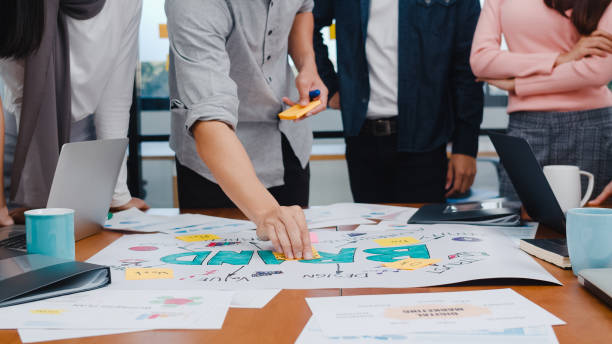 giovani imprenditori asiatici felici che incontrano idee di brainstorming su nuovi colleghi di progetti burocratici che lavorano insieme pianificando la strategia di successo godono di un lavoro di squadra in un piccolo ufficio moderno. - branding foto e immagini stock