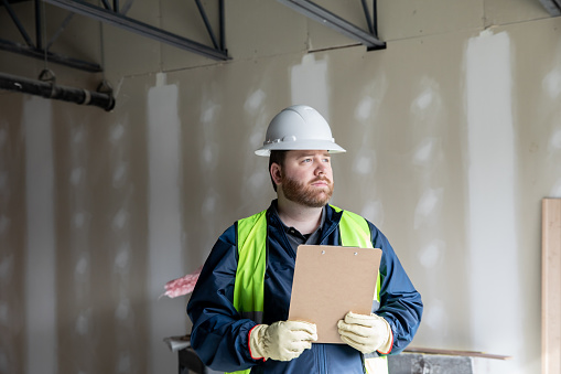Construction worker or engineer moves materials on jobsite and looks at plans on clipboard