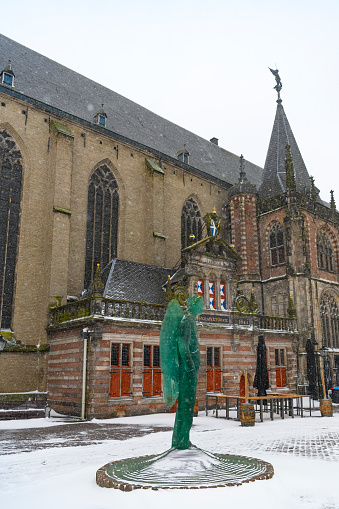 Heavy snowfall in the city center of Zwolle in Overijssel, during a cold winter day in The Netherlands. The glass statue of archangel Michael in the middle of the Grote markt.