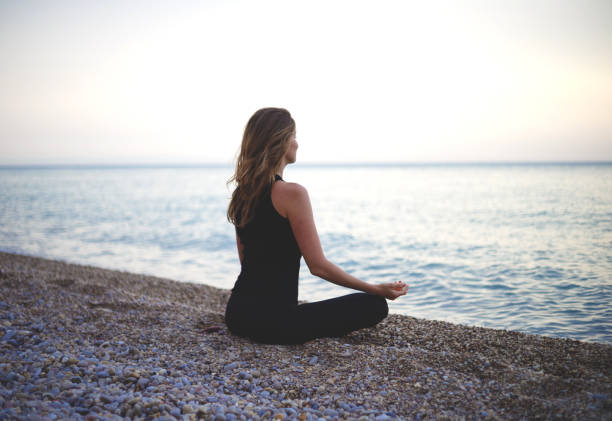 istock woman doing yoga at sunset on the beach 1301165635