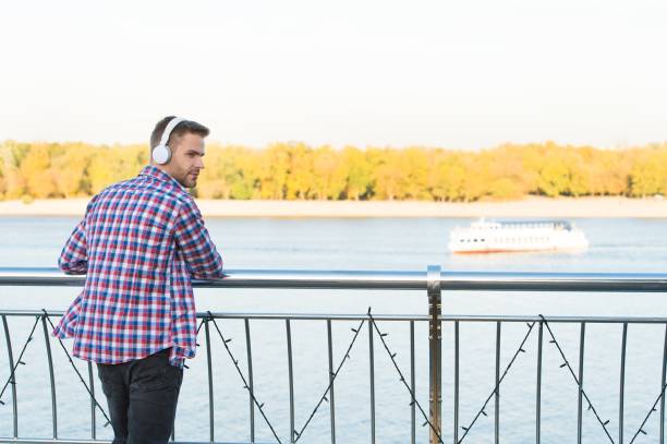 istock day time. audio book lesson. new digital technology. online education. handsome young man in headphones. modern design earphones. listen to music. guy casual style listening ebook 1301165645