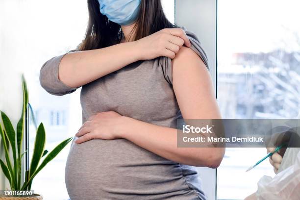 Doctor Giving Covid 19 Coronavirus Vaccine Injection To Pregnant Woman Doctor Wearing Blue Gloves Vaccinating Young Pregnant Woman In Clinic People Vaccination Concept Stock Photo - Download Image Now