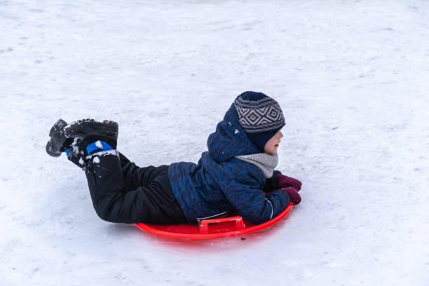 istock A little boy rides a sled from a winter slide. 1301167479