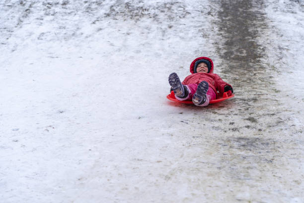 istock A little girl rides a sled from a winter slide 1301167511