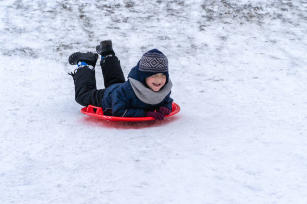 istock A little boy rides a sled from a winter slide. 1301167517
