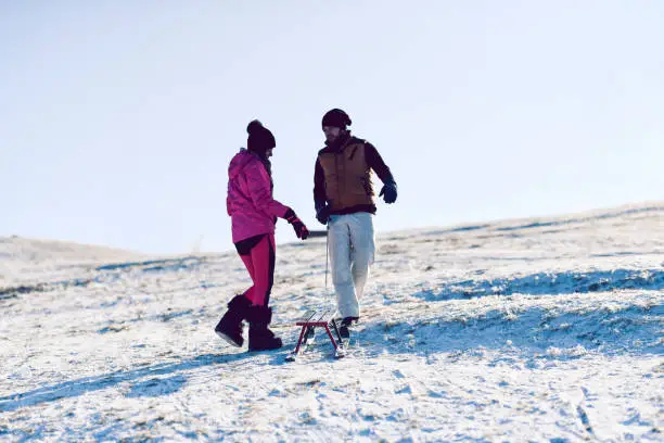 Couple Enjoying Time Spent Sleighing Together In Mountain Snow