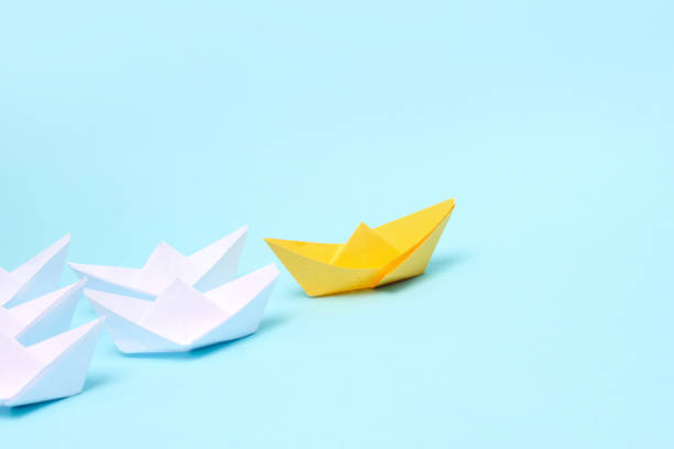 istock Leadership concept, blue paper ship leading among white on white background 1301170985