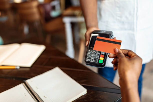 Customer making payment using credit card at bar Close-up image of female guest hand making mobile payment with her bank card cash register photos stock pictures, royalty-free photos & images