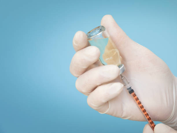 istock Hands in surgical gloves, vaccine into syringe on light blue background 1301172808