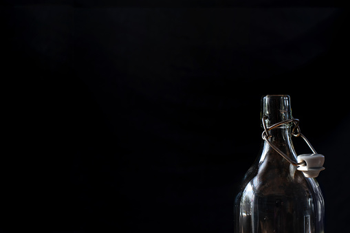 Bottle neck with old-fashioned top, close up, on black background, dark graphic design