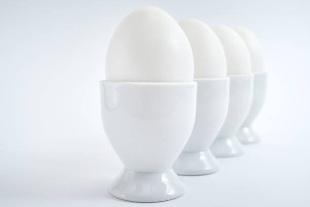 White eggs standing on egg cup isolated on white background, copy space. Row of boiled eggs in stand. Healthy food concept