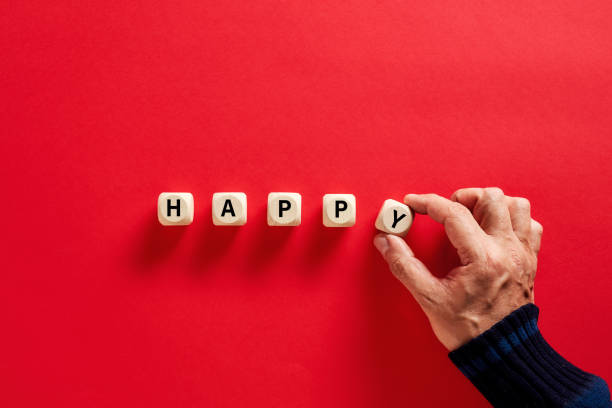 męska ręka układając drewniane bloki ze słowem szczęśliwym na czerwonym tle. szczęście, miłość i miłość - happy zdjęcia i obrazy z banku zdjęć