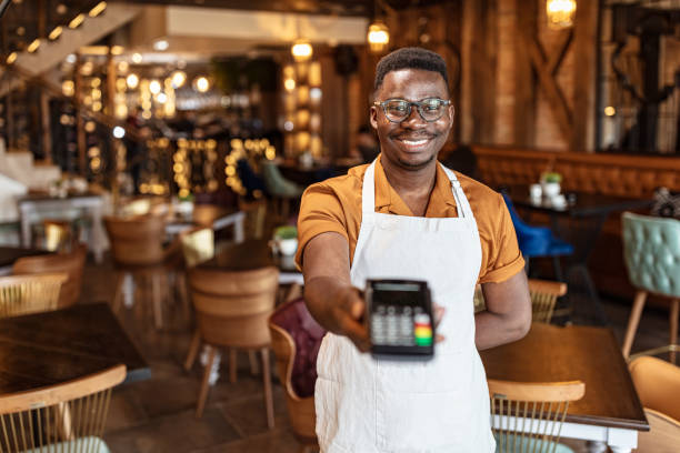 Ready for electronic payment Close up hands of cafeteria worker showing NFC for payment with contactless credit card. quick service restaurant cashier stock pictures, royalty-free photos & images