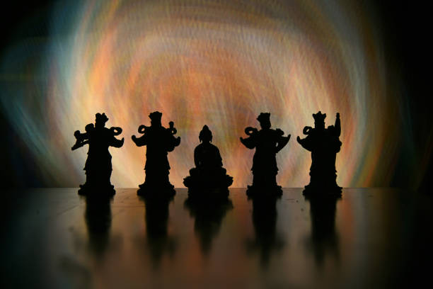 Close up of a buddha figurine seen slightly from the side and from above in front of lit candles. For mindfulness and wisdom concepts.  Selective focus and added grain. Part of an E+ and S+ series.