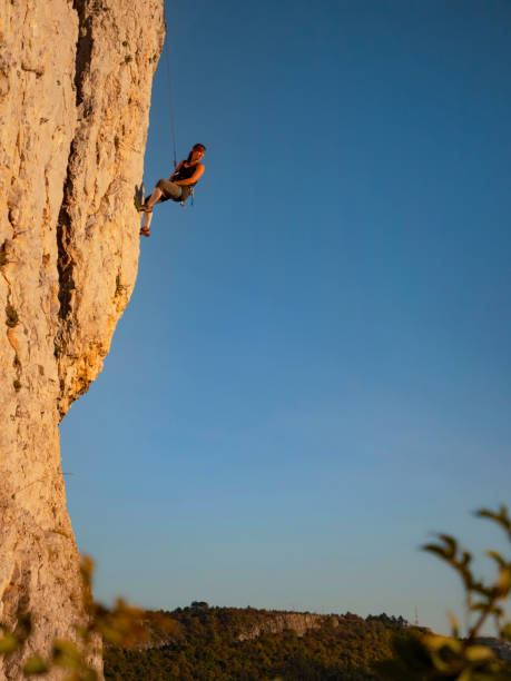 istock VERTICAL: Fit young woman stops and looks back at sunset while rock climbing. 1301179146