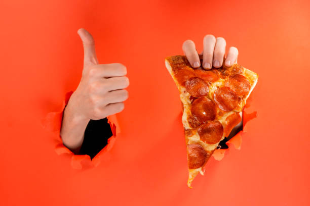 istock Hand holding a pizza slice and showing a thumb up 1301179293