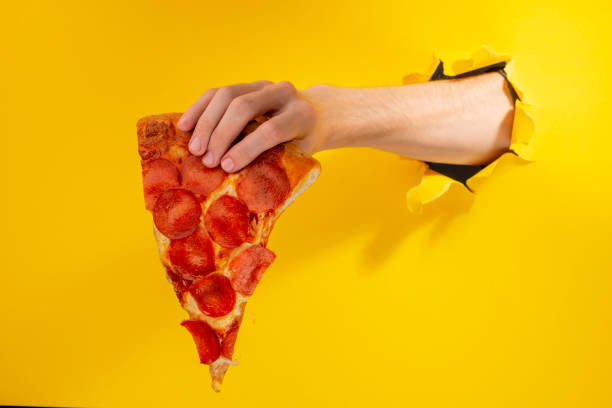 istock Hand holding a slice of Pepperoni pizza 1301180165