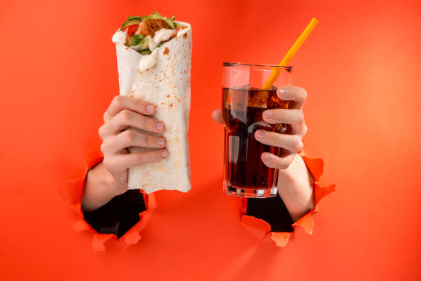 istock Hands holding a doner roll and a glass of cola 1301180325