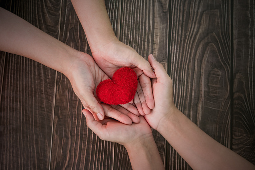 Two females people stack their hands together with red heart, with feelings of delivering or receiving love, care, safe, as Valentine's Day, Birthdays or other days. Family relationship, LGBT Concept