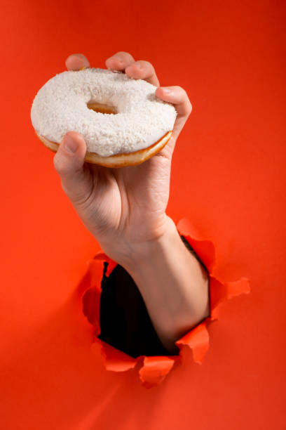 istock Hand showing a white donut through torn red paper background 1301180719