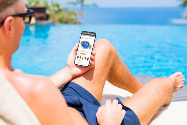 istock Man shopping online for a new watch while relaxing by the pool 1301182883