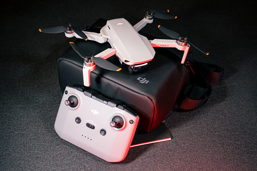 Kiev, Ukraine - February 02, 2021: Dji Mavic Mini 2 drone close-up. New unfolded quadcopter on black carrying bad with remote control on black background in red light