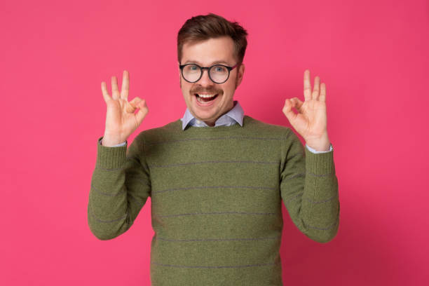 istock Young man with mustache gesturing OK sign on pink background 1301184976