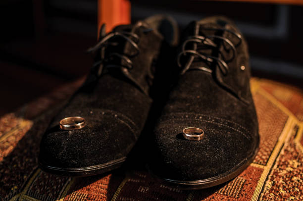 istock Gold wedding rings on black suede shoes 1301187339