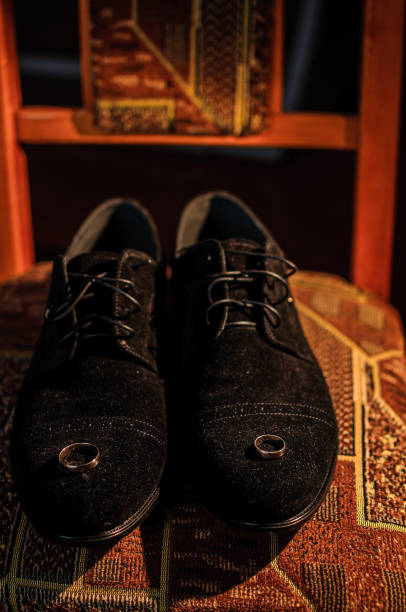 Gold wedding rings on black suede shoes