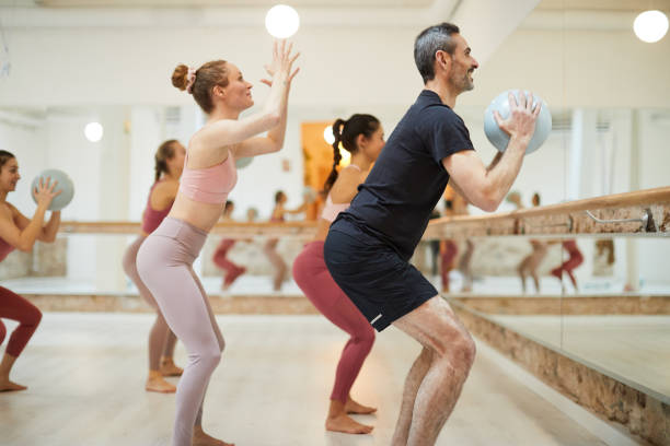 a female teacher conducts a barre fitness class. - women yoga yoga class mature adult imagens e fotografias de stock