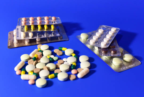 istock Pills and capsules on blue background. Medicine grade pharmaceutical tablets. 1301188174
