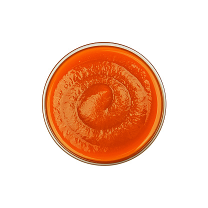 Close up one transparent glass bowl of orange sweet chili or sriracha sauce isolated on white background, top view, directly above