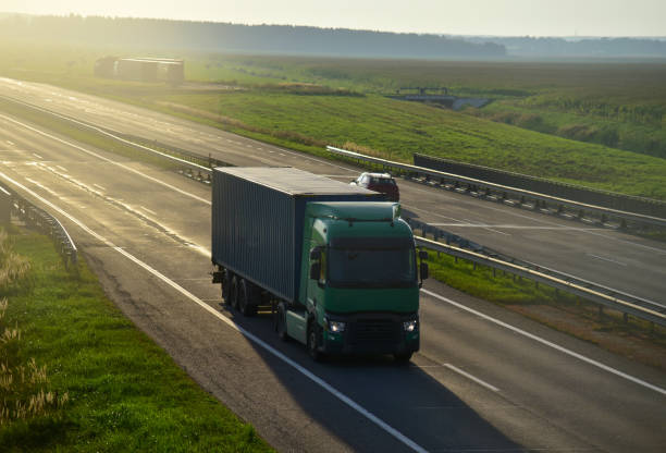 istock Semi truck transporting sea container on highway on sunset background 1301188924