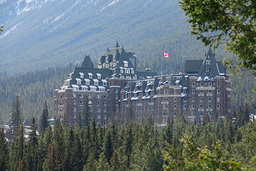 FAIRMONT BANFF SPRINGS HOTEL, BANFF, ALBERTA, CANADA, MARCH 2019: Lush evergreen forest surrounds the infamous haunted Fairmont Banff Springs Hotel. Scenic view of the spooky vacation resort in Canada